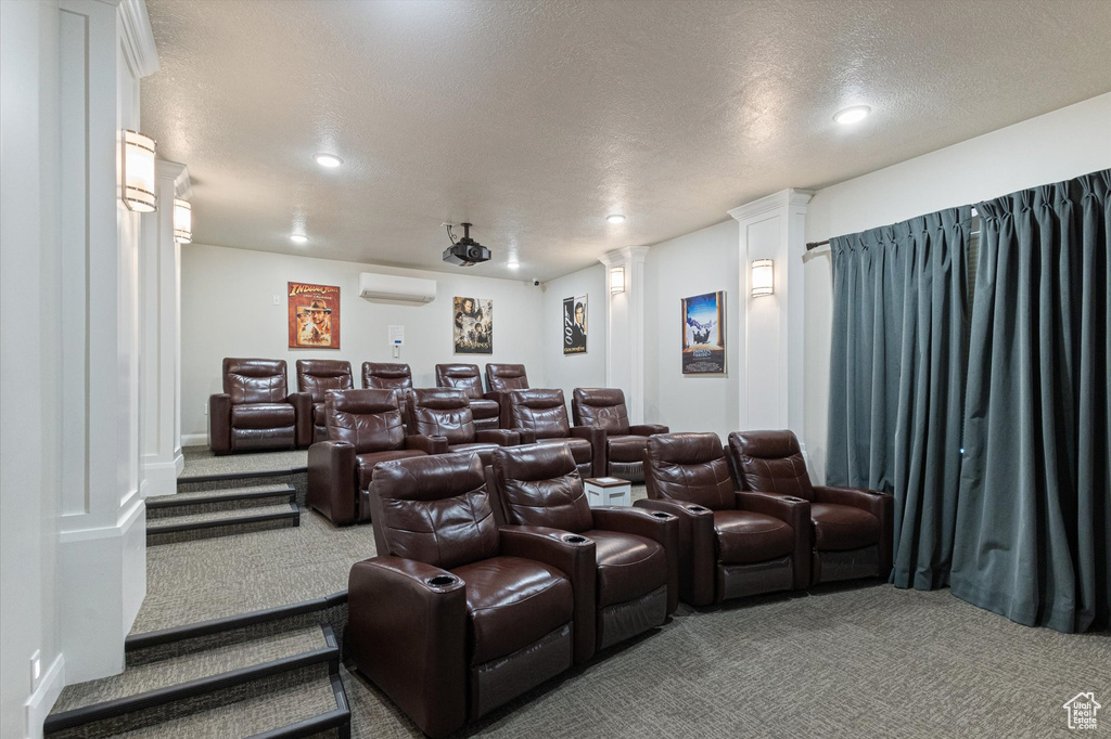 Carpeted cinema room with an AC wall unit, decorative columns, recessed lighting, and a textured ceiling