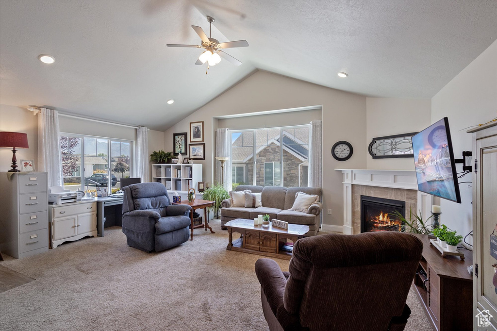 Living area with carpet floors, ceiling fan, vaulted ceiling, and a fireplace
