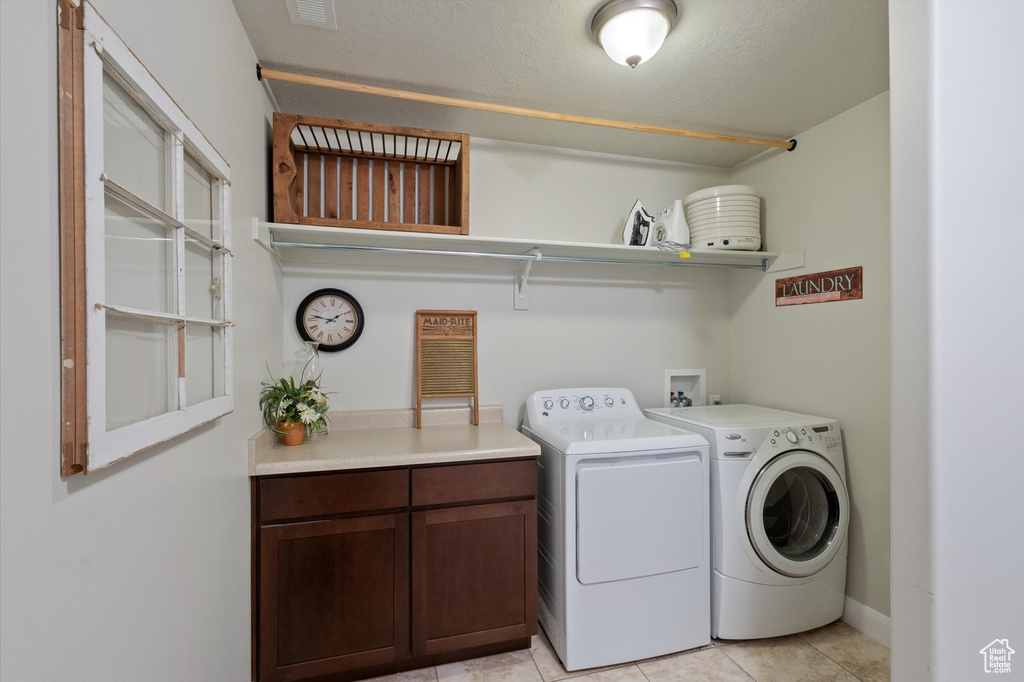 Laundry room with washer and clothes dryer, light tile patterned flooring, and cabinet space
