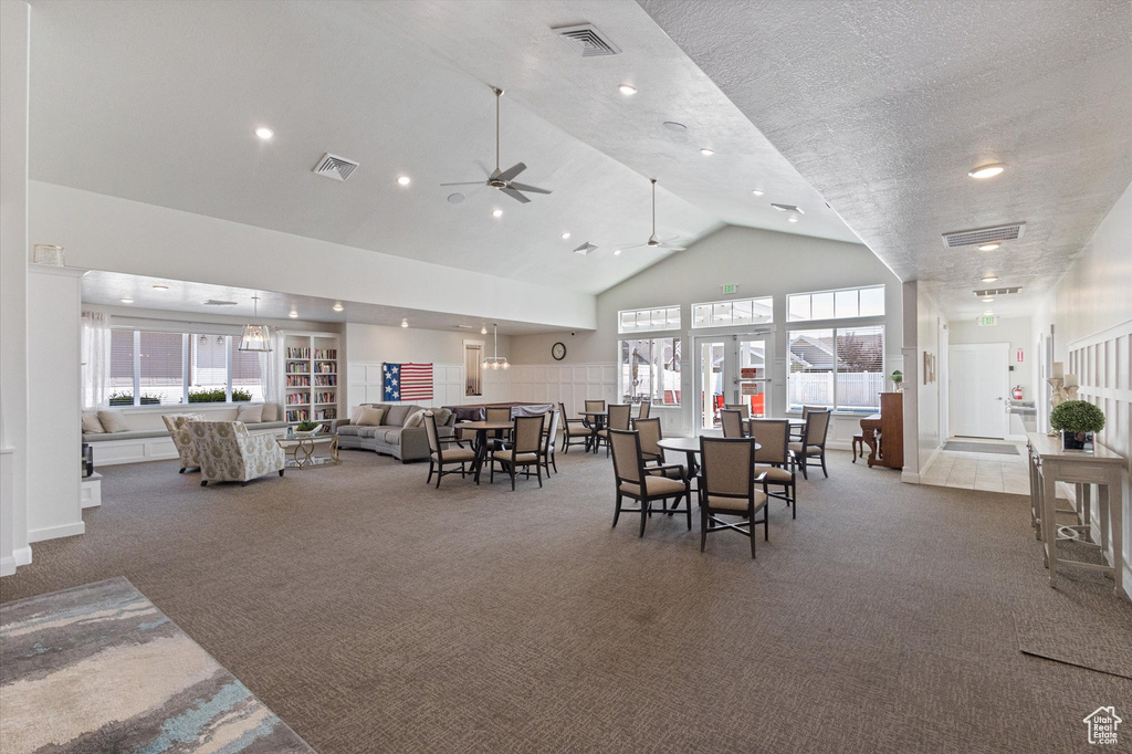 Carpeted dining room with high vaulted ceiling, ceiling fan, and recessed lighting