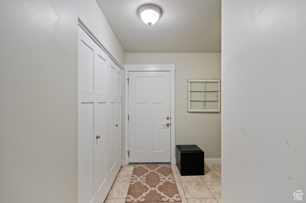 Doorway featuring light tile patterned floors and a textured ceiling