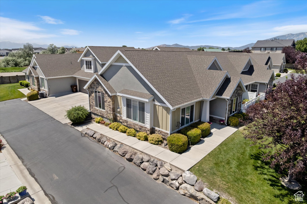 Craftsman inspired home featuring stone siding, roof with shingles, concrete driveway, a mountain view, and a residential view