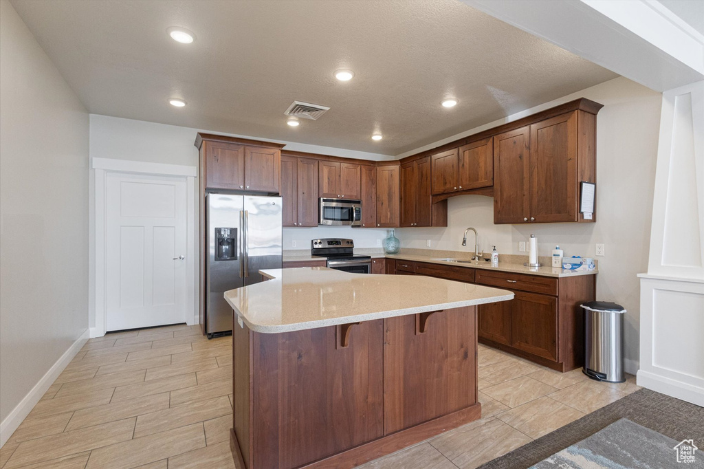 Kitchen featuring stainless steel appliances, a kitchen island, a breakfast bar area, and recessed lighting