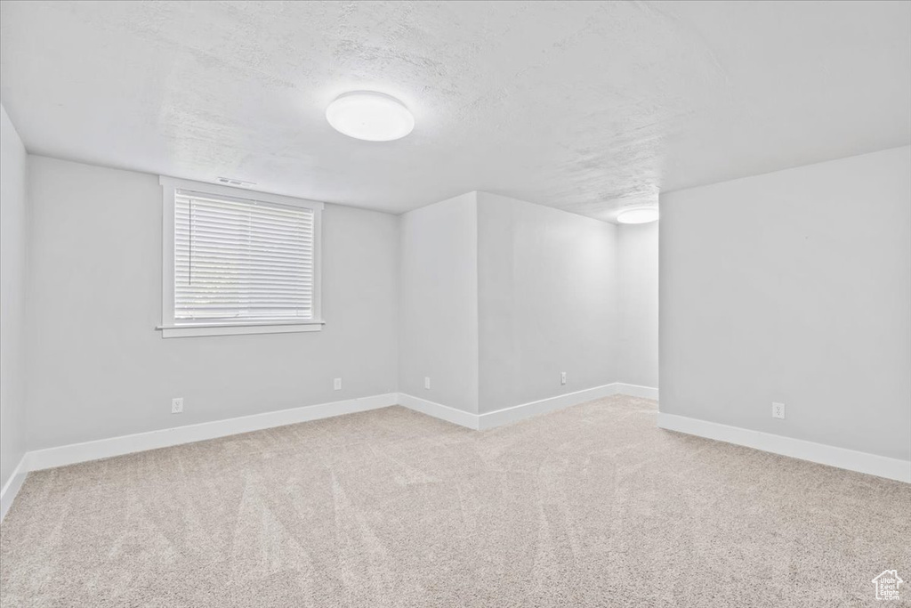 Unfurnished room featuring a textured ceiling and light colored carpet