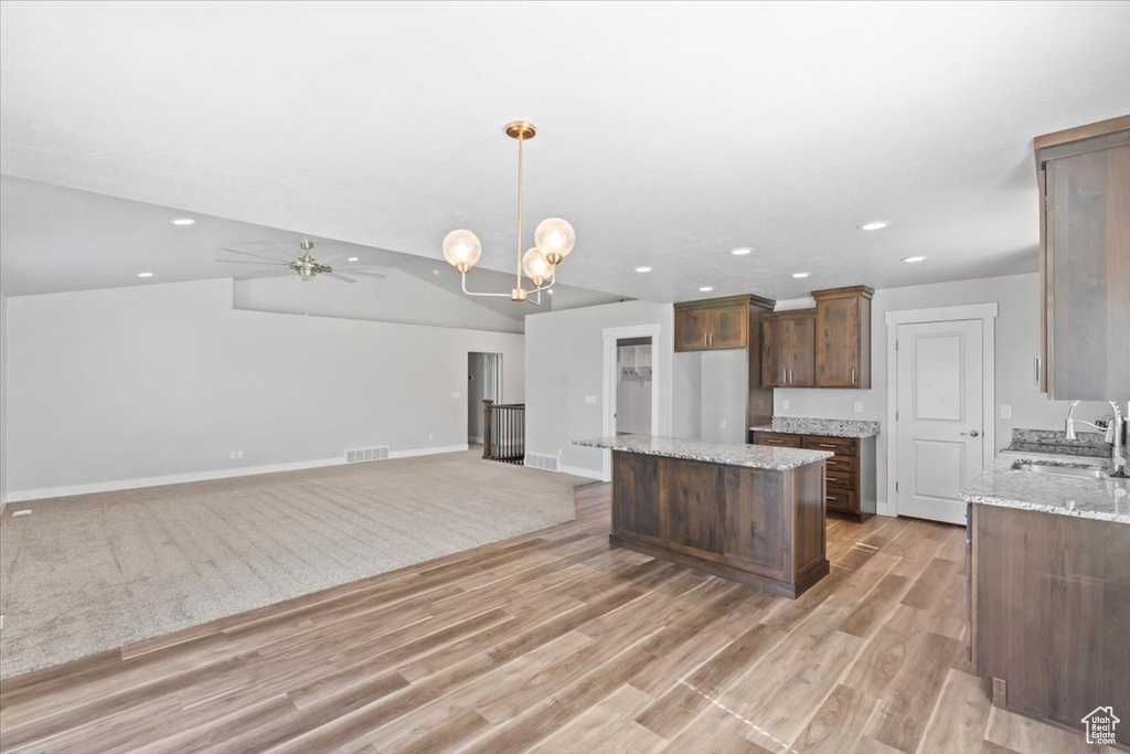 Kitchen featuring a center island, recessed lighting, light wood-type flooring, decorative light fixtures, and light stone countertops