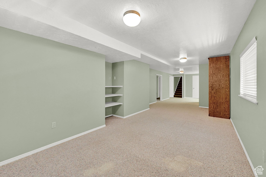 Spare room featuring built in shelves, carpet, stairway, and a textured ceiling