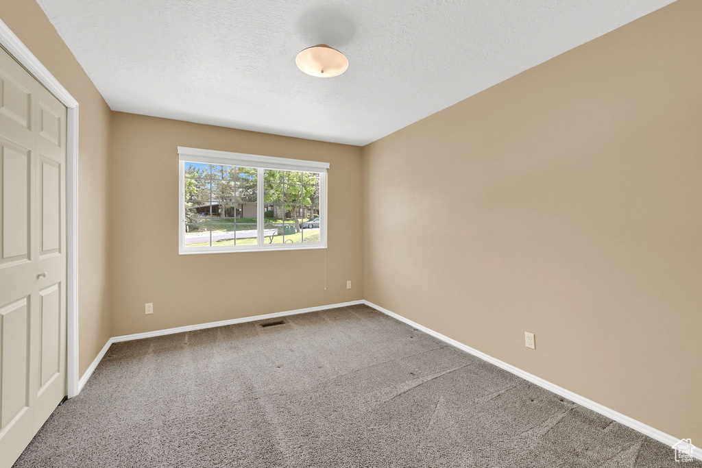 Unfurnished bedroom featuring carpet and a textured ceiling