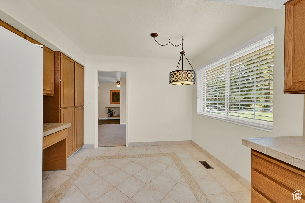 Unfurnished dining area featuring light tile patterned floors and ceiling fan