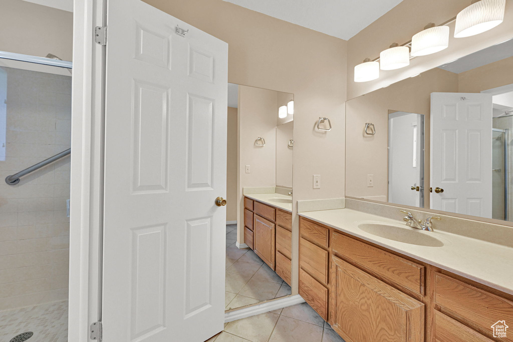Bathroom featuring double vanity, a shower stall, and tile patterned floors