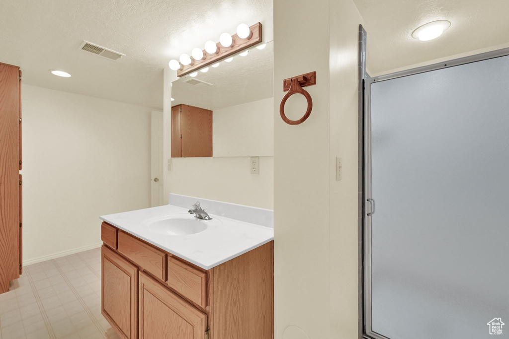 Full bathroom with vanity, tile patterned floors, and an enclosed shower