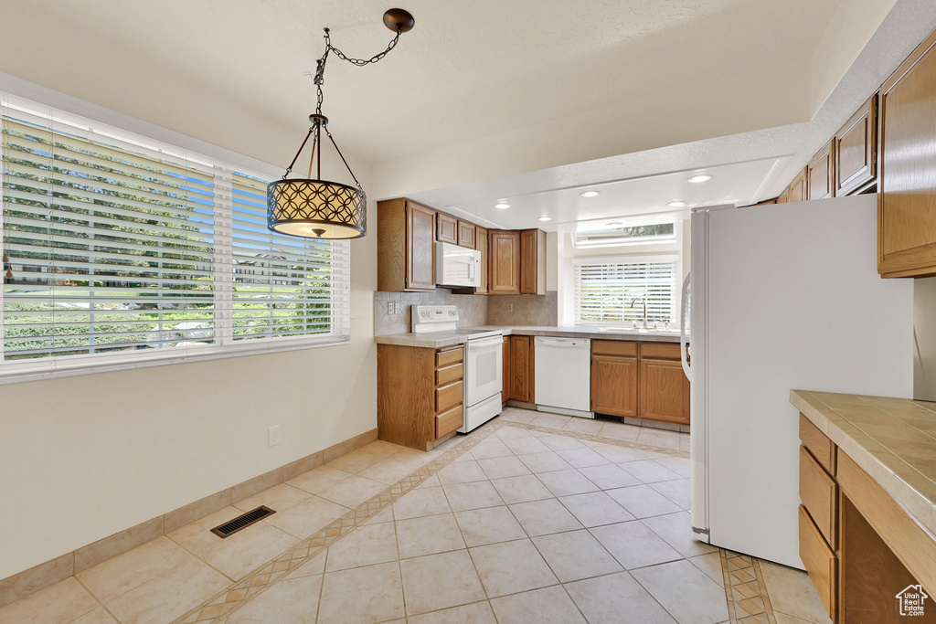 Kitchen with white appliances, light tile patterned floors, light countertops, backsplash, and recessed lighting