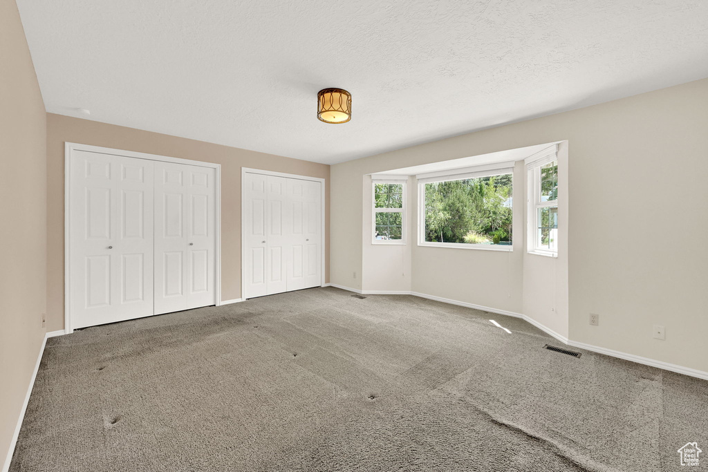 Unfurnished bedroom featuring two closets and carpet floors