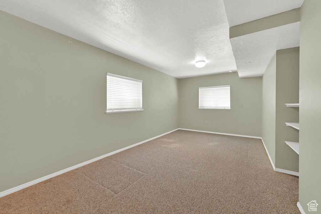 Carpeted empty room with baseboards and a textured ceiling