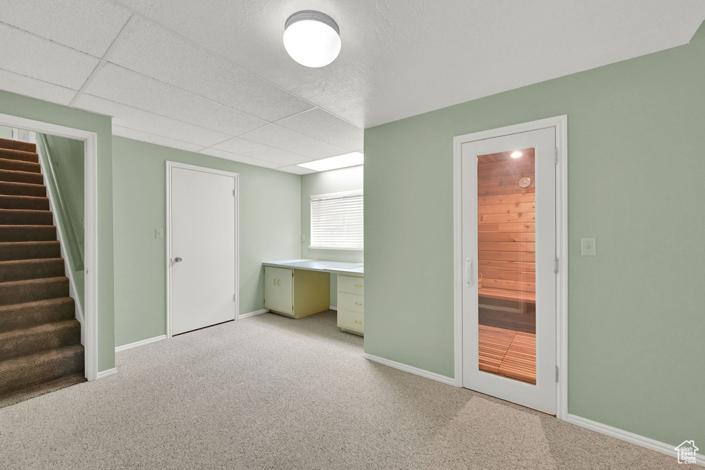 Unfurnished bedroom with light carpet, an office area, and a drop ceiling
