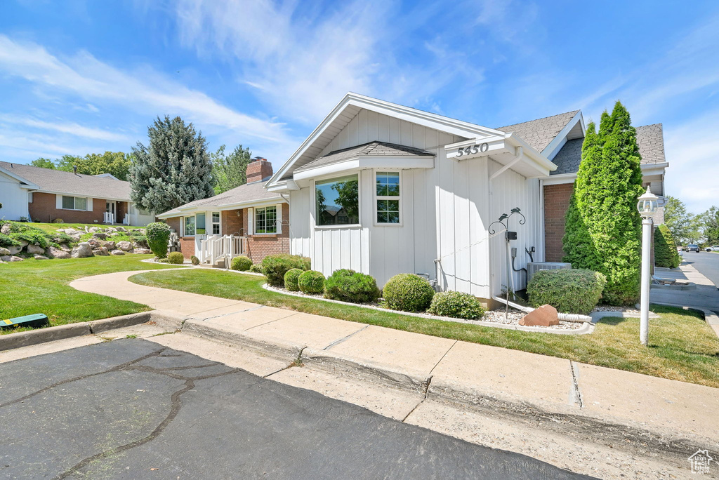 Ranch-style home featuring a chimney, a front lawn, brick siding, and a shingled roof