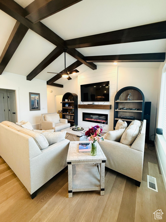 Living area with light wood-type flooring and a glass covered fireplace