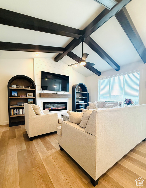 Living area with light wood-type flooring, a glass covered fireplace, and a ceiling fan