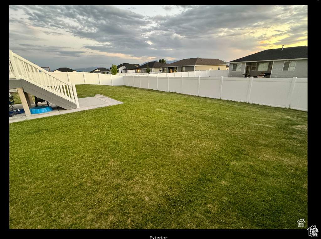 Fenced backyard featuring stairs, a residential view, and a patio area