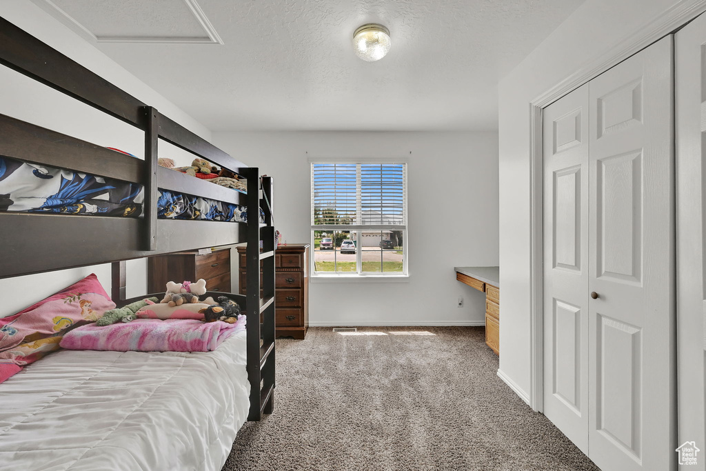 Carpeted bedroom with attic access and a closet
