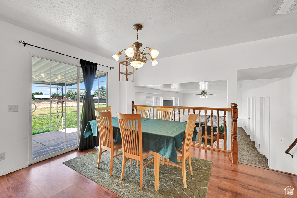 Dining room featuring a chandelier, wood finished floors, a textured ceiling, and ceiling fan