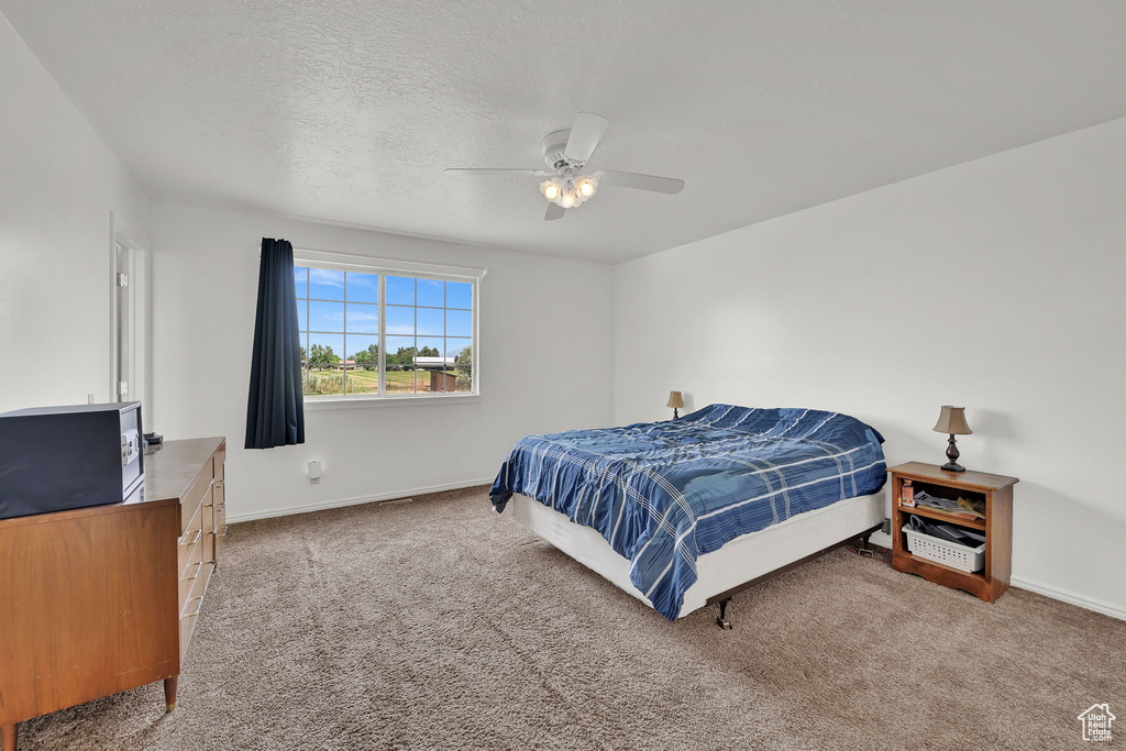 Carpeted bedroom with a ceiling fan and a textured ceiling