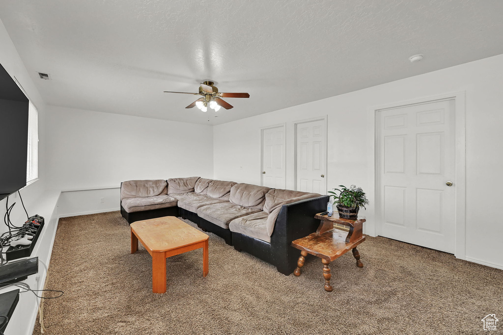 Living area featuring ceiling fan and carpet flooring