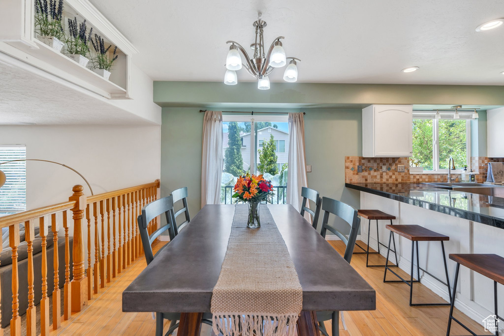 Dining room with light wood-style flooring, recessed lighting, a chandelier, and healthy amount of natural light