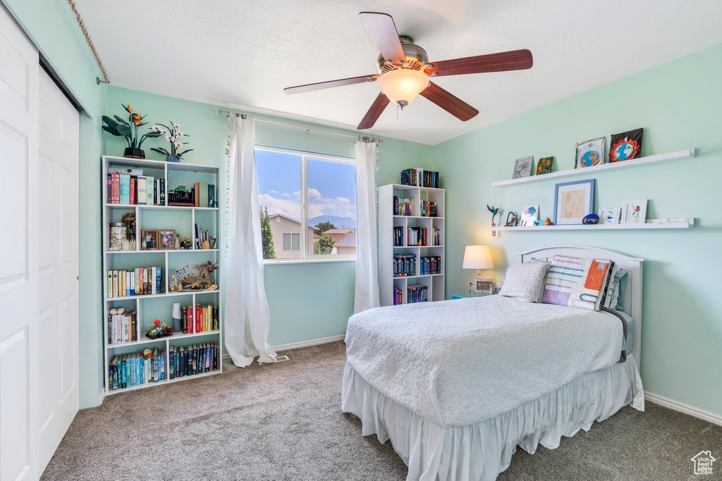 Carpeted bedroom with a ceiling fan and a closet