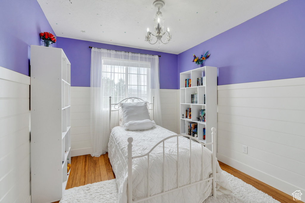 Bedroom featuring a chandelier, wood finished floors, and wainscoting
