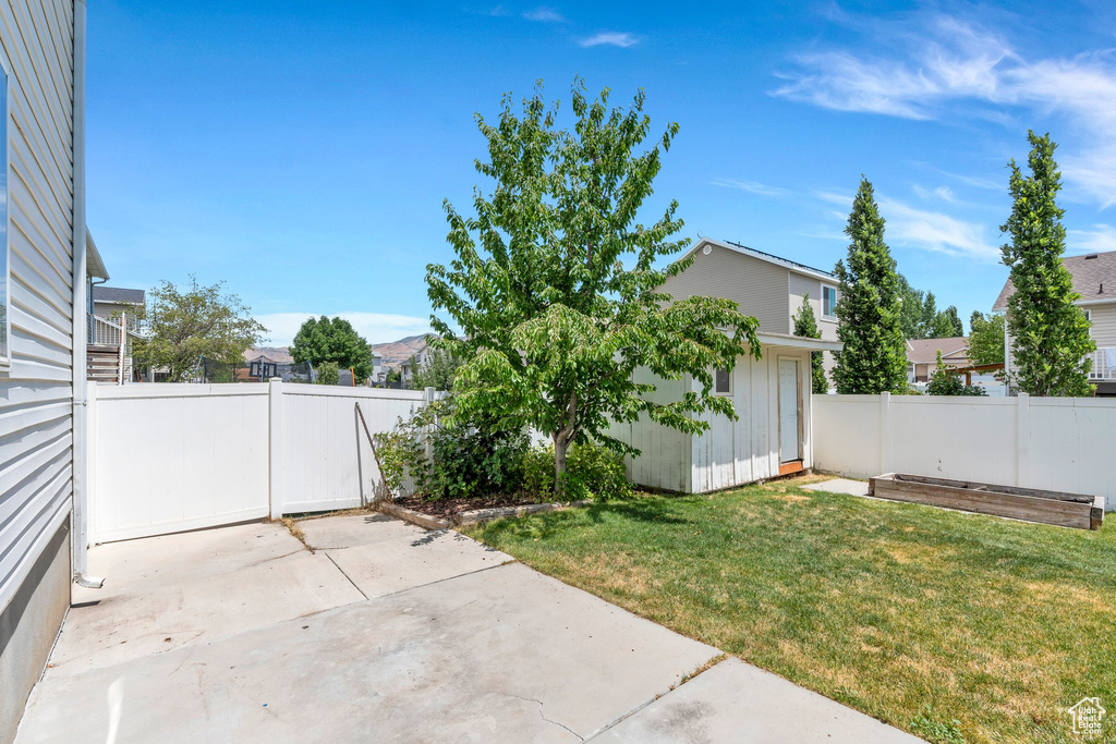 Fenced backyard featuring a patio and a shed