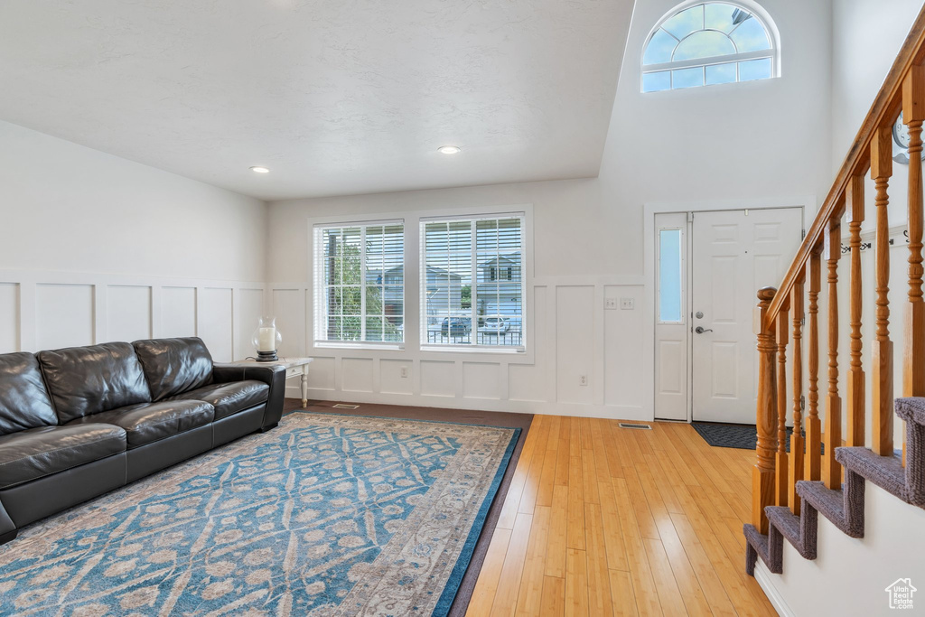 Living area featuring stairway, a decorative wall, light wood-style flooring, a wainscoted wall, and recessed lighting
