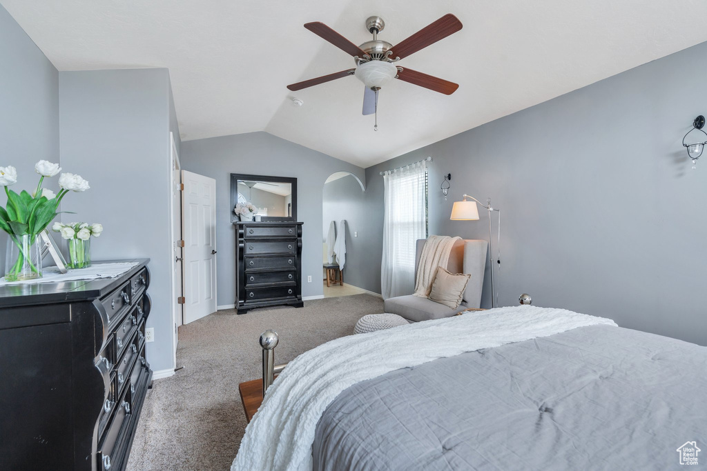 Bedroom with vaulted ceiling, carpet flooring, arched walkways, and a ceiling fan