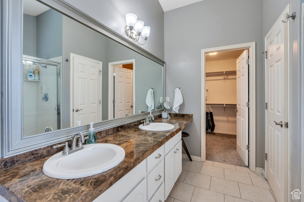 Bathroom featuring tile patterned floors, a shower stall, double vanity, and a walk in closet