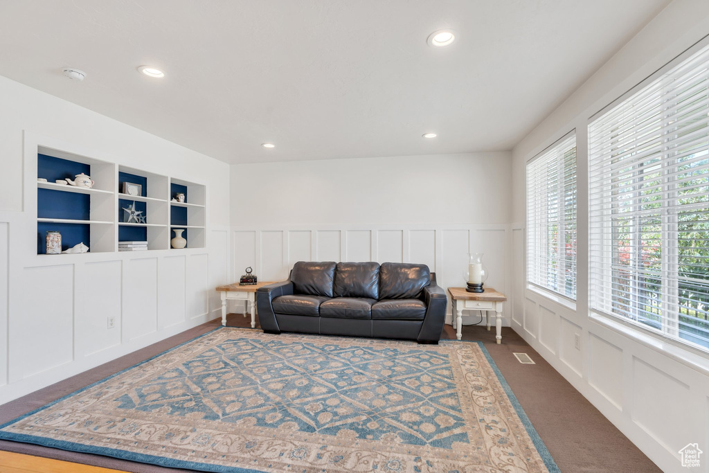 Living room featuring a decorative wall, dark colored carpet, recessed lighting, and a wainscoted wall
