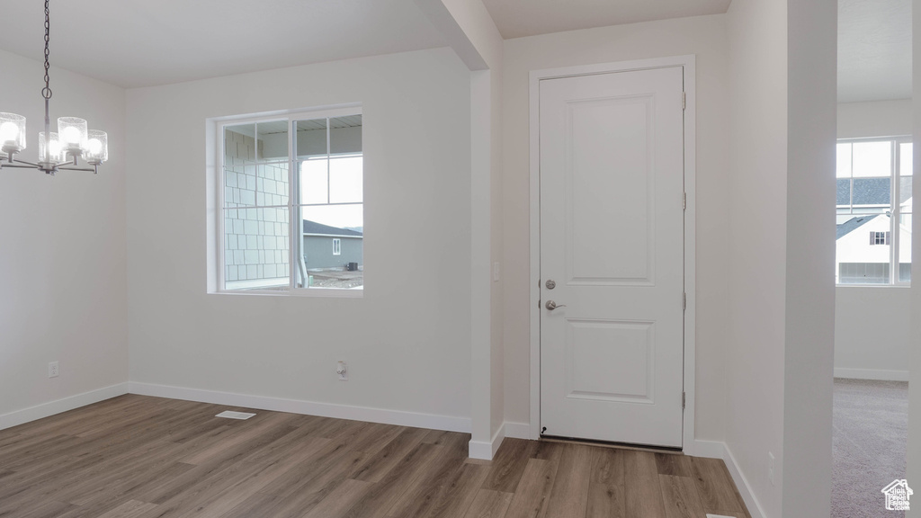 Entrance foyer with wood finished floors and a chandelier