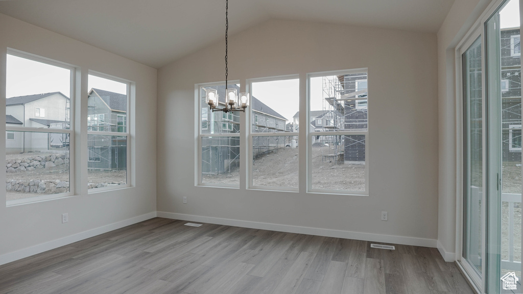 Unfurnished dining area featuring wood finished floors, a chandelier, and lofted ceiling