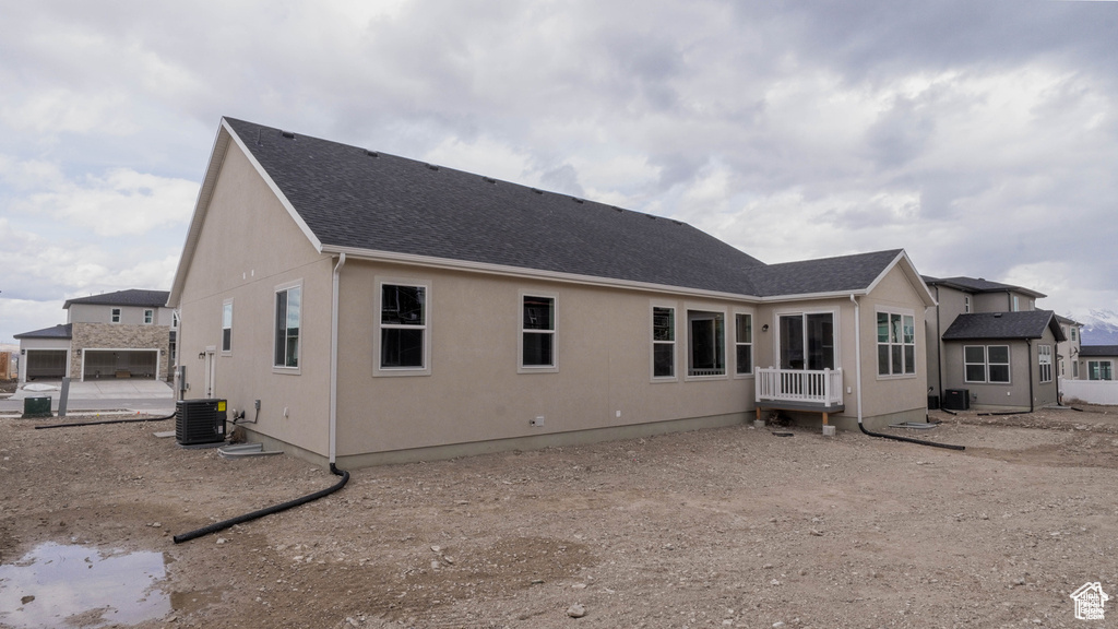 Back of property featuring roof with shingles and stucco siding