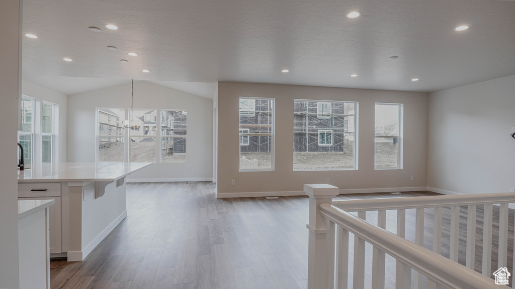 Kitchen with wood finished floors, recessed lighting, white cabinets, light countertops, and a chandelier