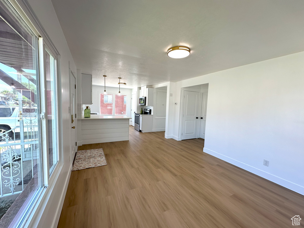 Unfurnished living room featuring light wood-style floors and baseboards
