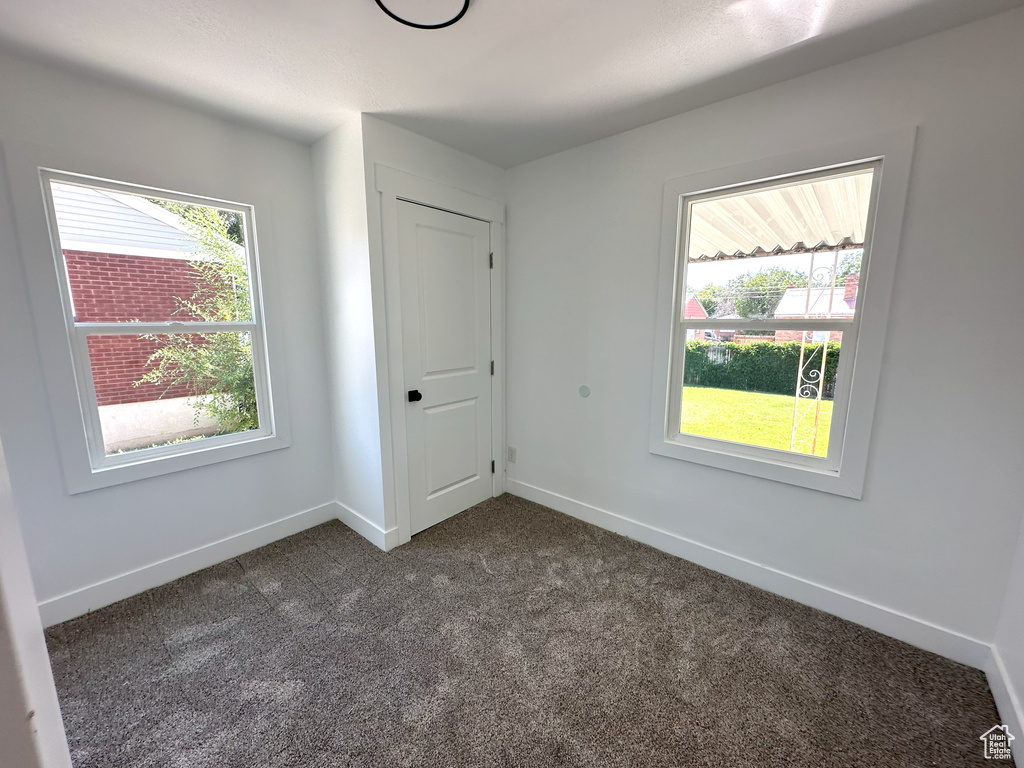 Unfurnished bedroom with dark colored carpet and baseboards