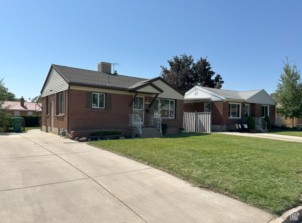 Ranch-style house with brick siding, a front yard, a chimney, and concrete driveway