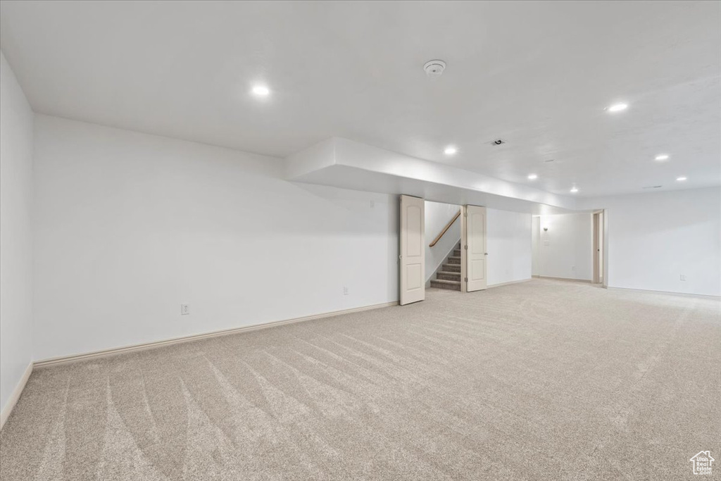 Finished basement featuring light carpet, recessed lighting, and stairway