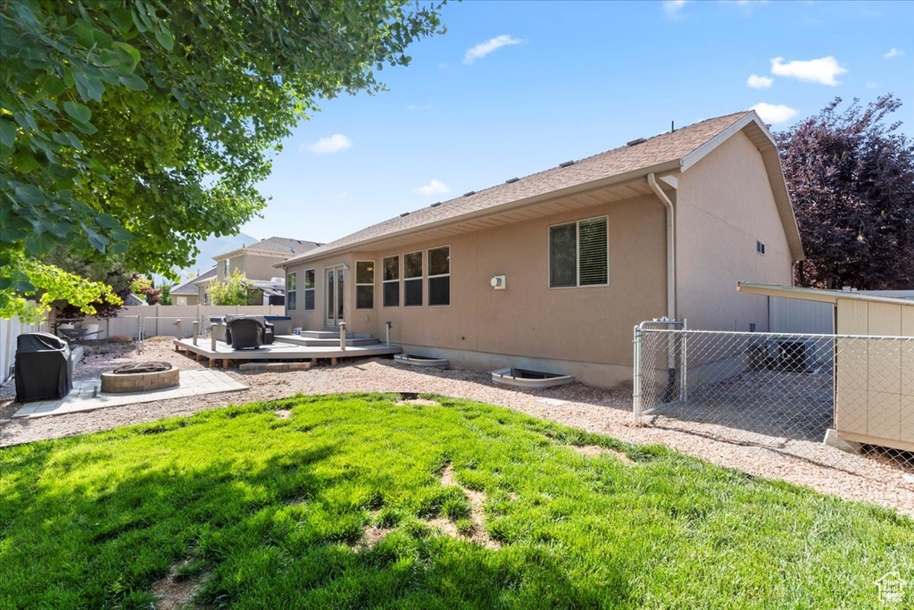 Rear view of house with a fire pit, a fenced backyard, a deck, and stucco siding