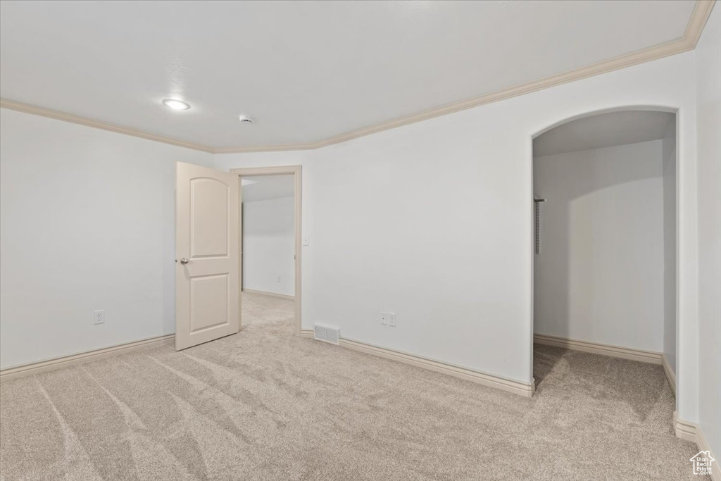 Carpeted empty room featuring ornamental molding, arched walkways, and recessed lighting