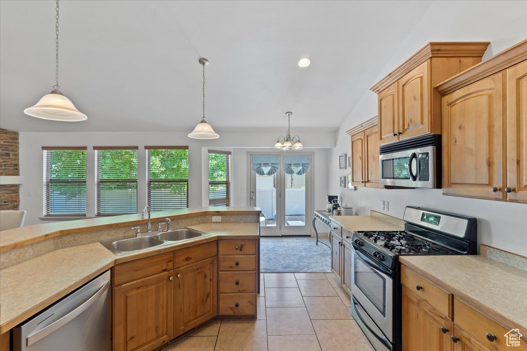 Kitchen featuring appliances with stainless steel finishes, light countertops, vaulted ceiling, hanging light fixtures, and a chandelier