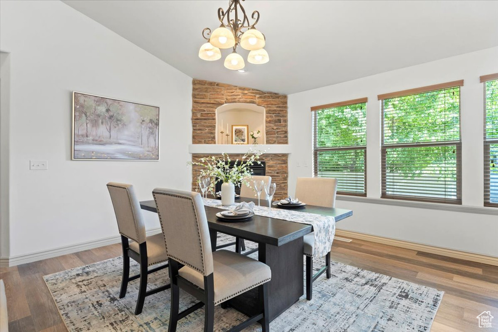 Dining space featuring vaulted ceiling, a chandelier, and wood finished floors