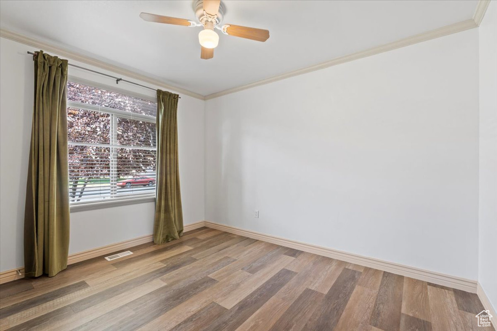Spare room featuring wood finished floors, ornamental molding, and ceiling fan