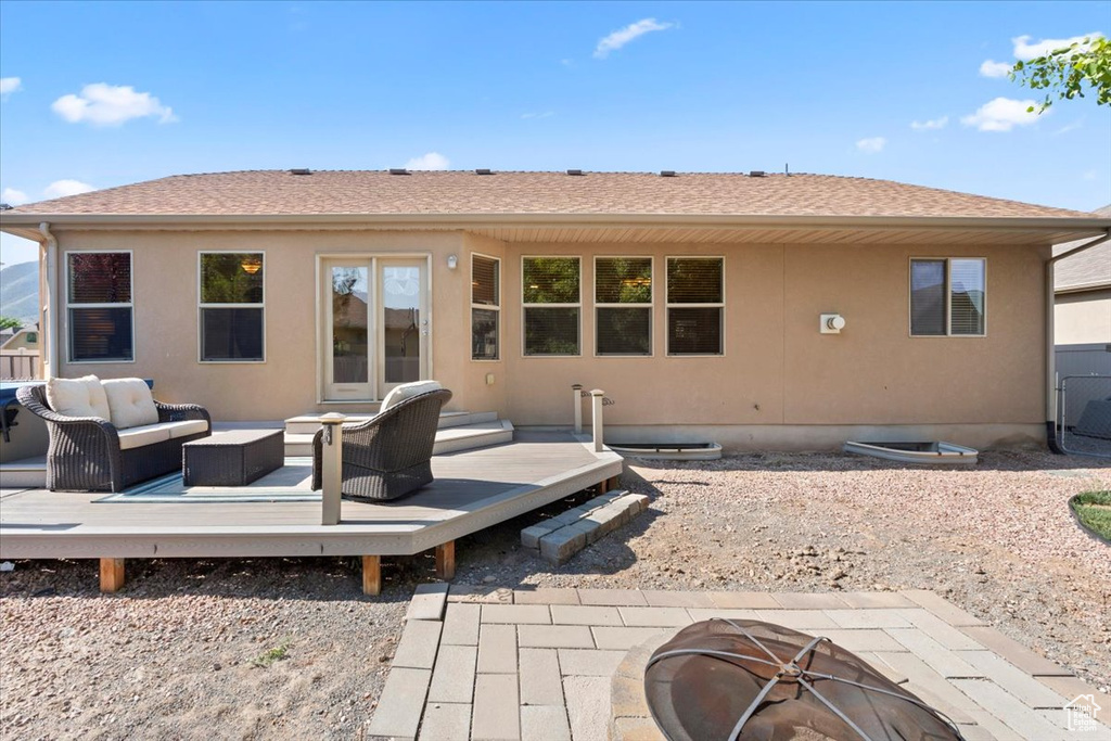 Rear view of property featuring a deck, an outdoor living space with a fire pit, and a shingled roof