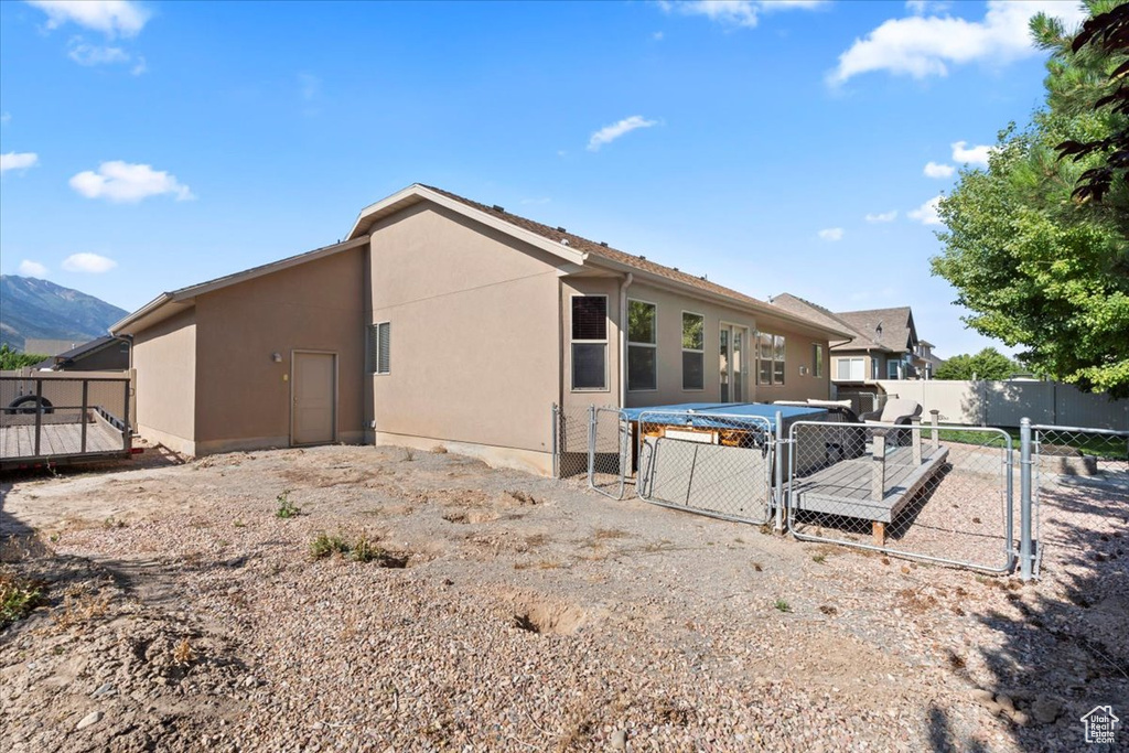 Back of house with a gate and stucco siding