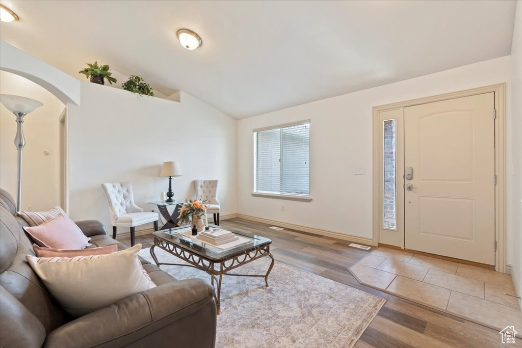 Living area featuring wood finished floors, arched walkways, and vaulted ceiling